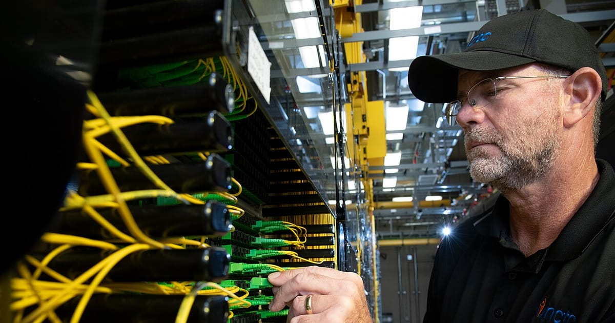 A technician inspecting fiber-optic patch panels in a data center